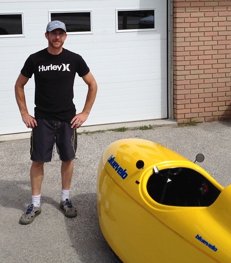 Randy standing in front of a Yellow velomobile